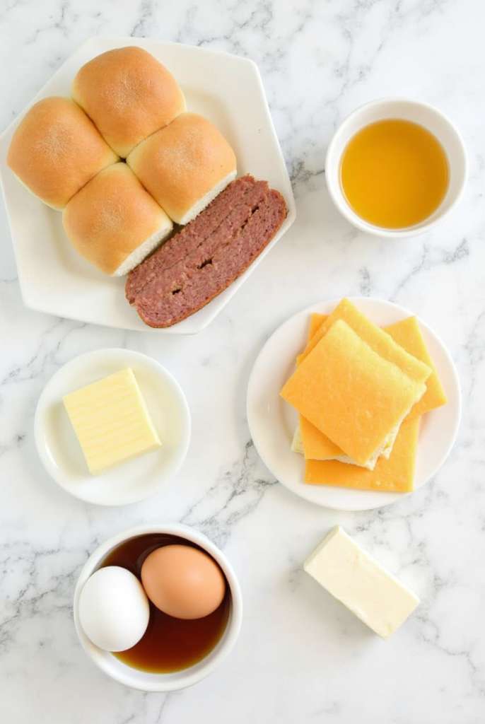 Step-by-step preparation of breakfast sliders with sausage, eggs, and cheese on a marble countertop