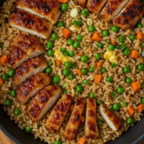 Close-up of Bang Bang Chicken Fried Rice in a bowl with spicy sauce and green onions