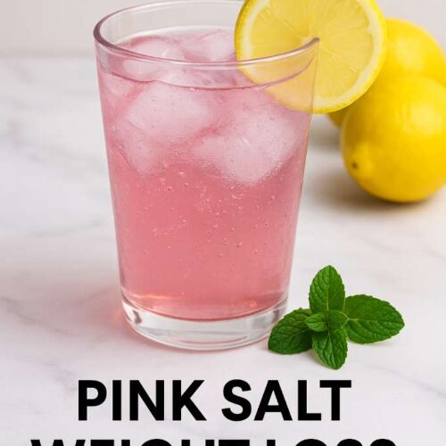 Glass of pink salt weight loss drink with lemon slice and mint on marble table