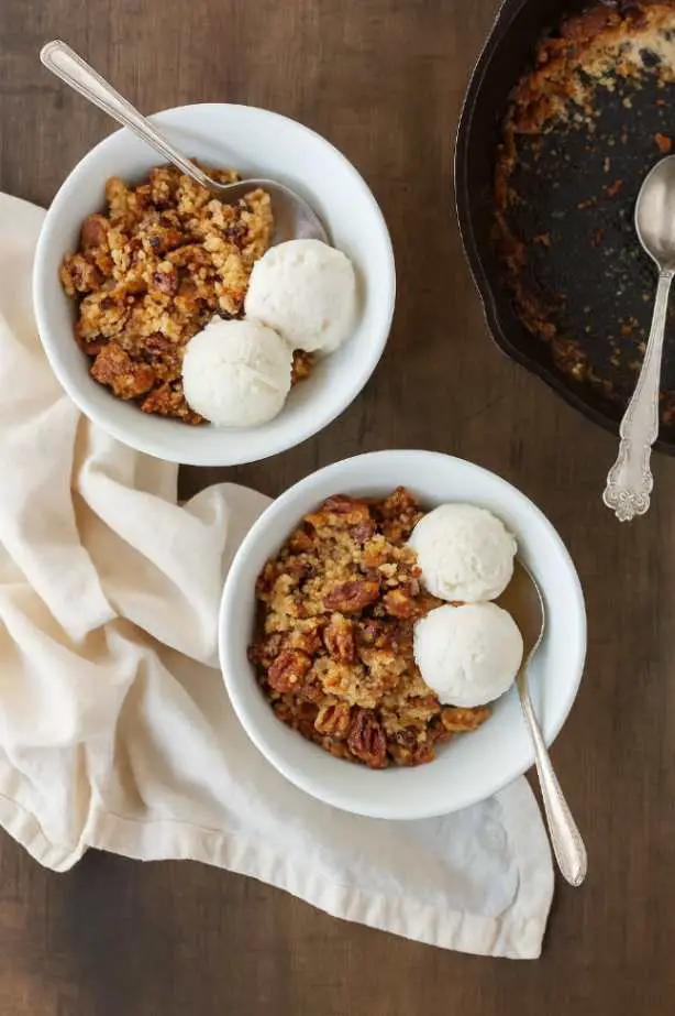 Close-up of pecan pie dump cake with vanilla ice cream served in white bowls