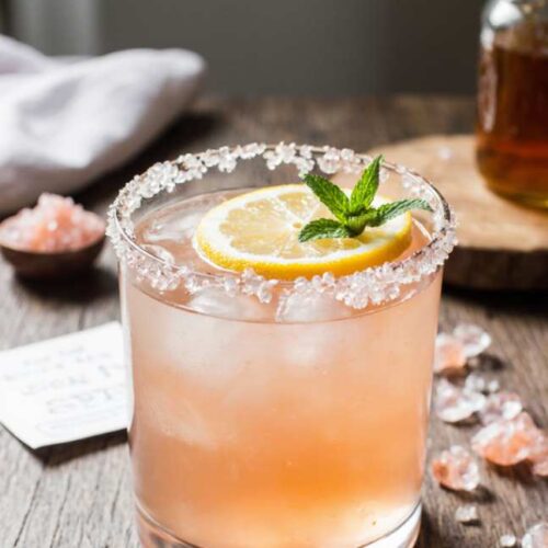 Glass of pink salt weight loss drink with lemon slice and mint on marble table
