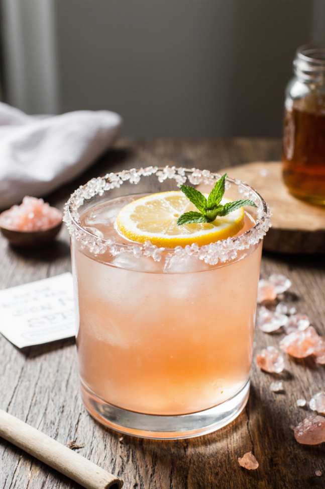 Glass of pink salt weight loss drink with lemon slice and mint on marble table