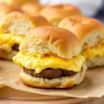 Step-by-step preparation of breakfast sliders with sausage, eggs, and cheese on a marble countertop