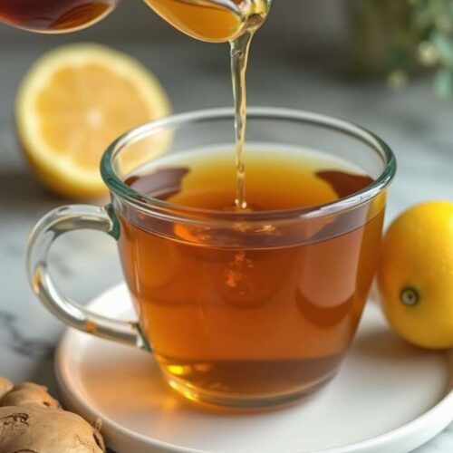 Close-up of Natural Mounjaro Tea in a clear glass mug with lemon and ginger beside it