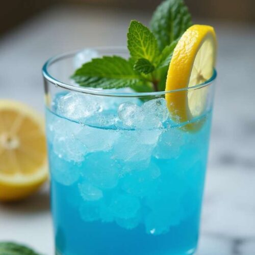 Blue Salt Trick drink in a clear glass with Persian salt crystals, fresh lemon slices, and mint on a neutral background