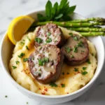 Garlic butter steak bites with parmesan cream sauce served over mashed potatoes on a marble table