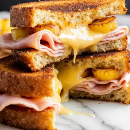 Golden crispy hash brown Hawaiian toastie stacked with melted cheese, ham, and pineapple on a wooden board