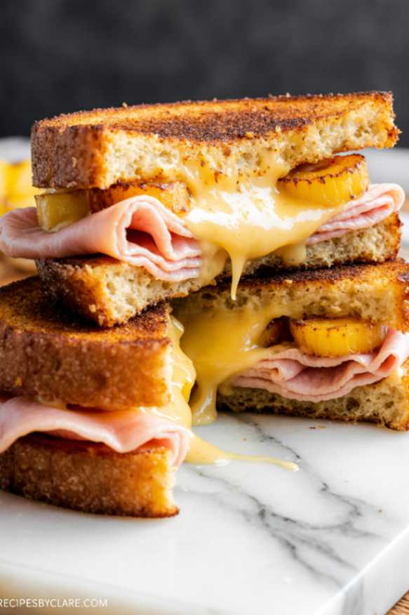 Golden crispy hash brown Hawaiian toastie stacked with melted cheese, ham, and pineapple on a wooden board