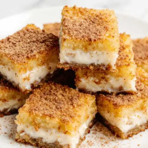 Golden air-fried milk squares dusted with cinnamon sugar on a white plate