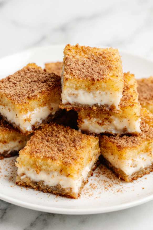 Golden air-fried milk squares dusted with cinnamon sugar on a white plate