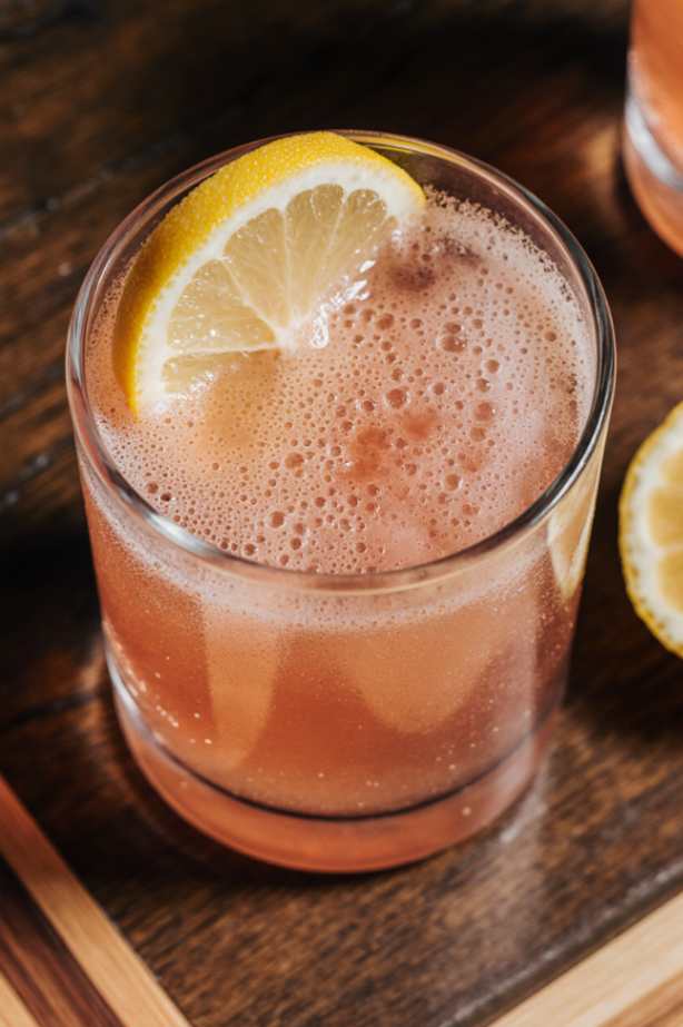 Flat lay of a glass of pink drink with pink salt, lemon, and mint on a light background. Natural detox drink for weight loss.