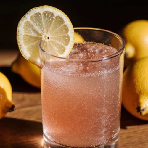 Flat lay of a glass of pink drink with pink salt, lemon, and mint on a light background. Natural detox drink for weight loss.