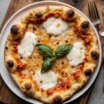 Finished Neapolitan pizza served on a wooden board with fresh basil on top