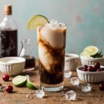 Glass of dirty soda with creamy swirl and garnishes on a rustic table